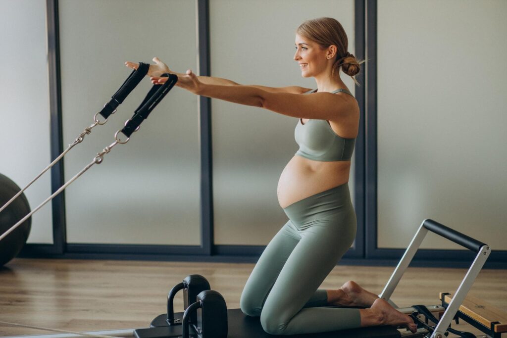 Donna in gravidanza si allena alla macchina pilates reformer PILATES IN GRAVIDANZA